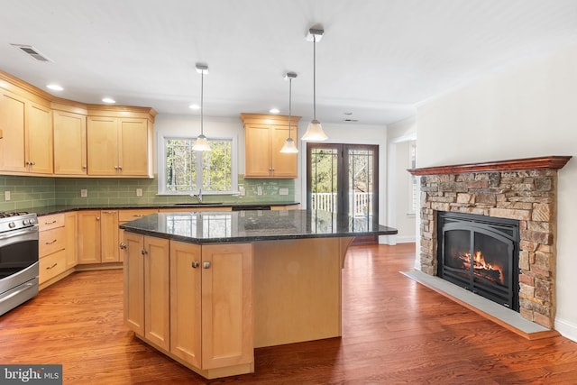 kitchen featuring visible vents, light brown cabinets, stainless steel gas range oven, and light wood finished floors