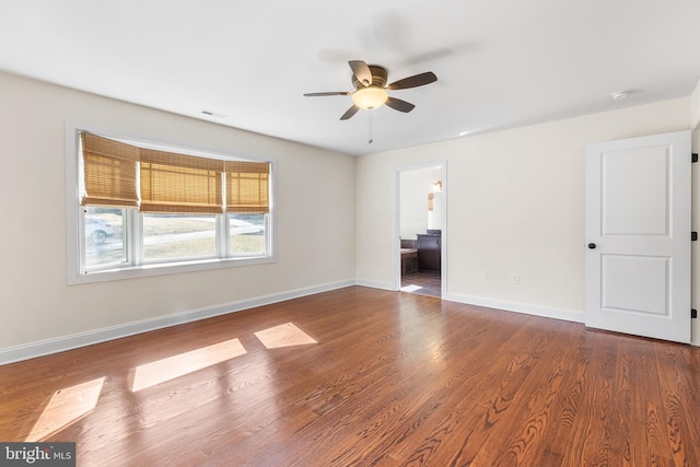 unfurnished room with dark wood-style floors, a ceiling fan, visible vents, and baseboards