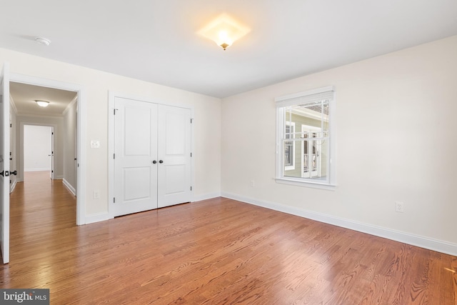 unfurnished bedroom featuring a closet, light wood-style flooring, and baseboards