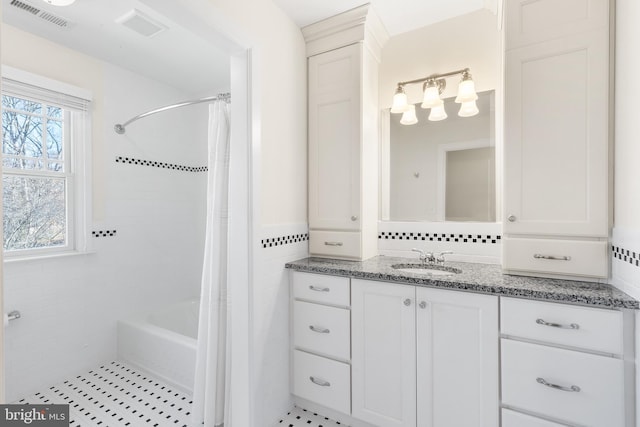 bathroom with shower / bath combo, visible vents, tile walls, and vanity