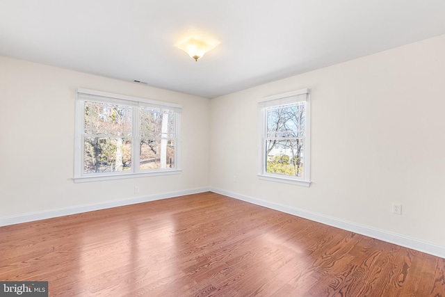 spare room featuring baseboards and wood finished floors