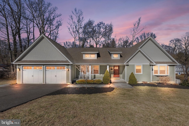 view of front of house featuring an attached garage, a front lawn, aphalt driveway, and roof with shingles