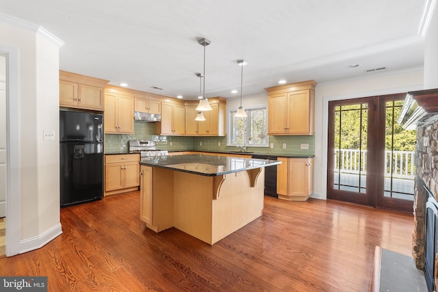 kitchen with gas range, light brown cabinetry, and freestanding refrigerator