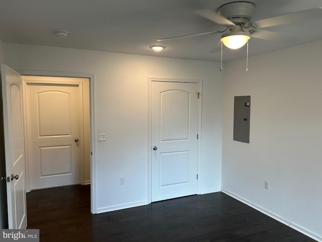 unfurnished bedroom featuring dark wood-style floors, a ceiling fan, electric panel, and baseboards