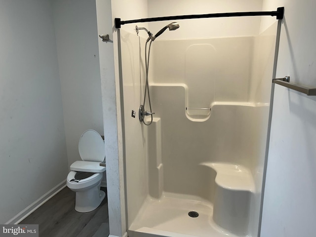 full bathroom featuring a stall shower, wood finished floors, toilet, and baseboards