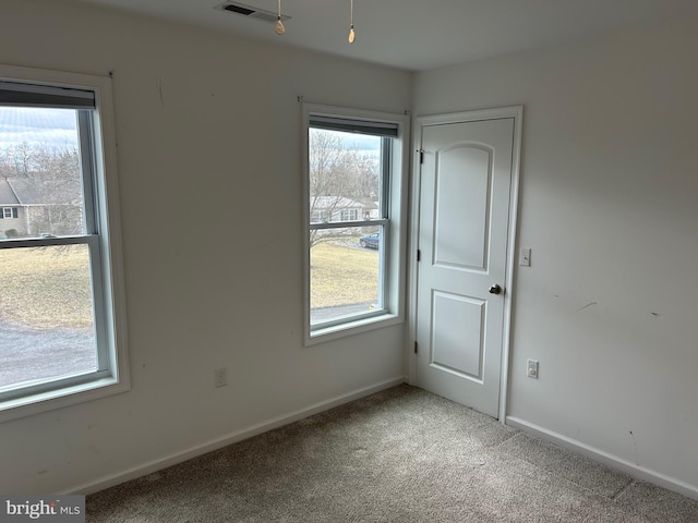 carpeted empty room with plenty of natural light, visible vents, and baseboards