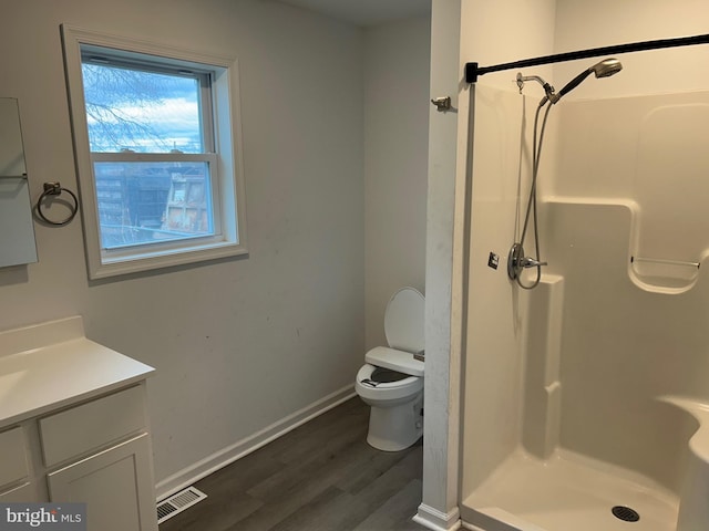 bathroom featuring visible vents, a shower stall, vanity, and wood finished floors