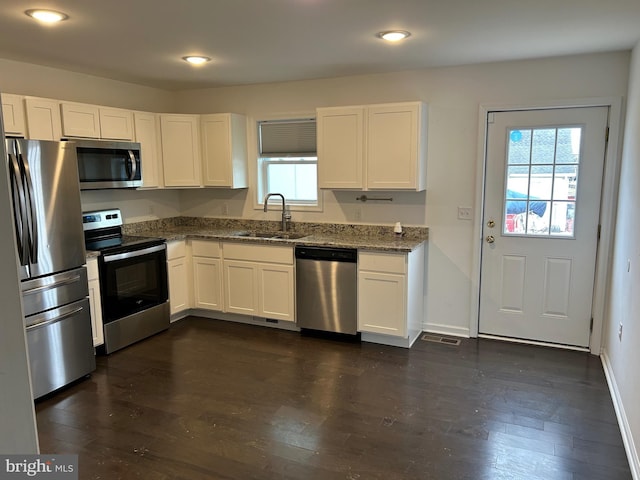 kitchen with appliances with stainless steel finishes, dark wood-type flooring, a sink, and white cabinets