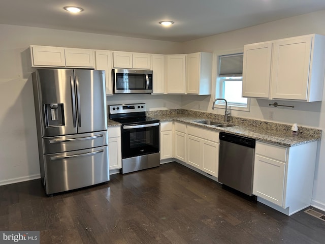 kitchen featuring stainless steel appliances, visible vents, dark wood-type flooring, white cabinetry, and a sink