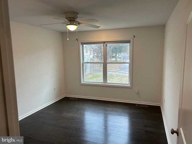 empty room featuring ceiling fan, dark wood-type flooring, visible vents, and baseboards