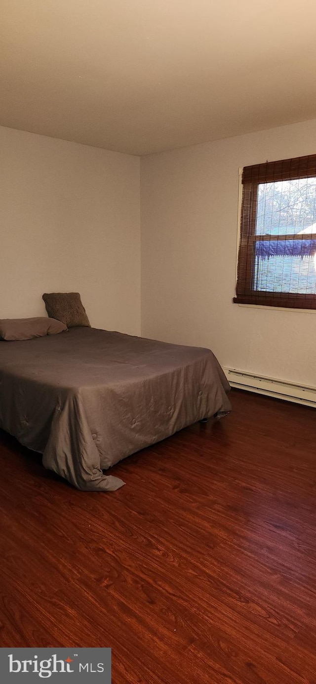 bedroom with a baseboard radiator and wood finished floors