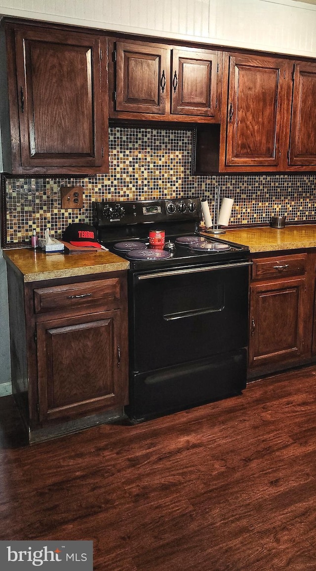 bar with backsplash, dark wood finished floors, and black electric range oven