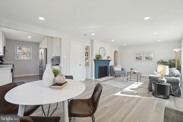 dining room with light wood-type flooring, baseboards, and a fireplace