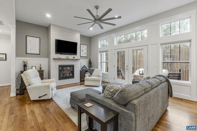 living area featuring a large fireplace, a healthy amount of sunlight, and wood finished floors