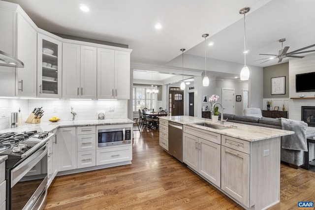 kitchen with light wood finished floors, open floor plan, white cabinets, stainless steel appliances, and a sink