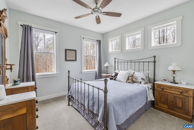 bedroom with light colored carpet, a ceiling fan, and baseboards