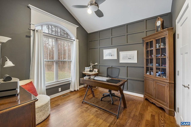 office with visible vents, wood finished floors, vaulted ceiling, and a decorative wall