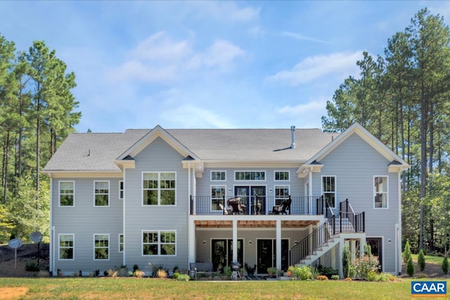 rear view of house featuring stairway, a lawn, a deck, and roof with shingles