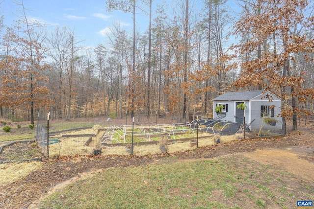 view of yard featuring fence, an outdoor structure, and a garden