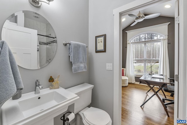 bathroom with toilet, vaulted ceiling, wood finished floors, a ceiling fan, and a sink