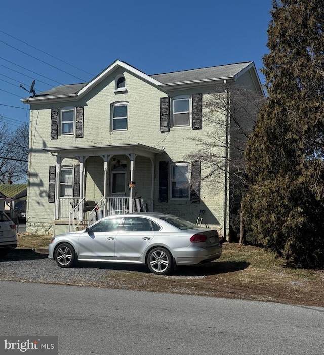 view of front of house featuring brick siding and covered porch