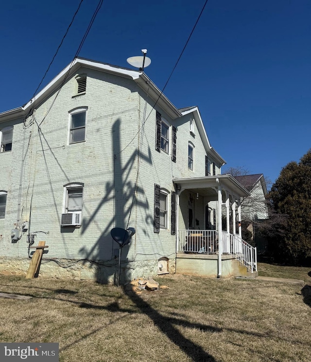 view of property exterior featuring a porch, cooling unit, brick siding, and a yard