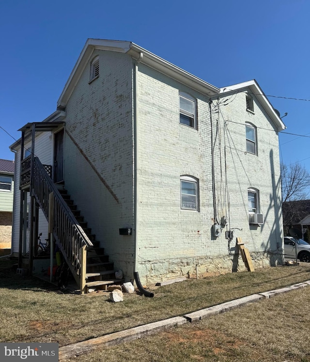 view of home's exterior featuring cooling unit, brick siding, and stairs