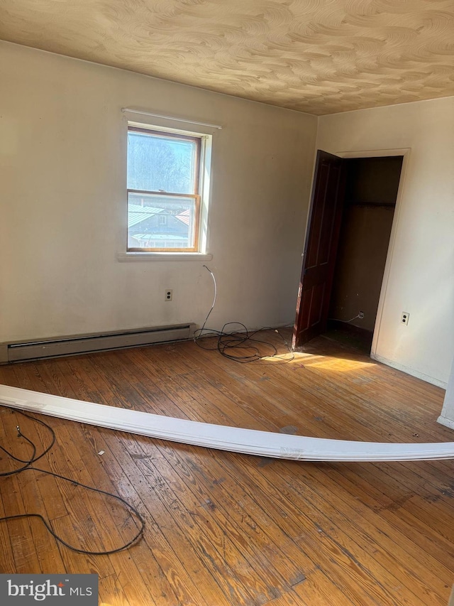 empty room featuring hardwood / wood-style floors and baseboard heating