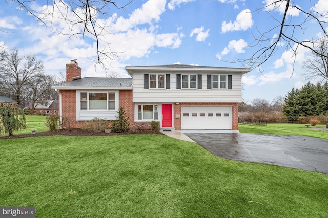 split level home with brick siding, a chimney, a front yard, a garage, and driveway