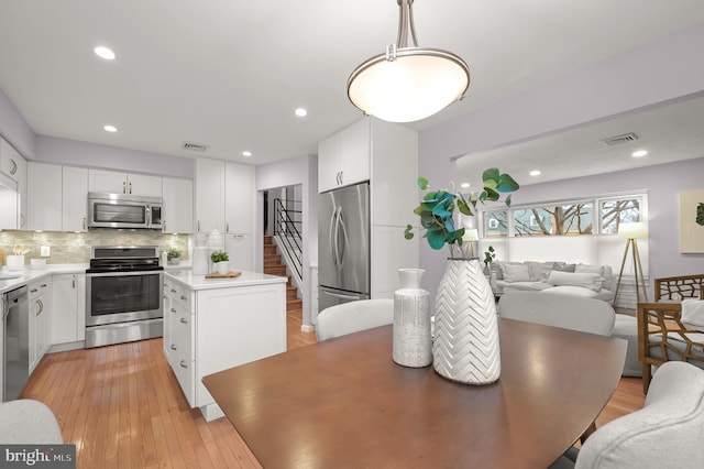 kitchen featuring open floor plan, stainless steel appliances, a kitchen island, and visible vents