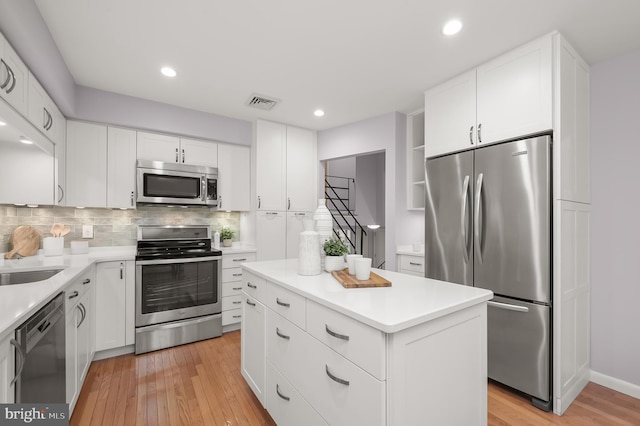 kitchen featuring stainless steel appliances, visible vents, light countertops, backsplash, and light wood finished floors