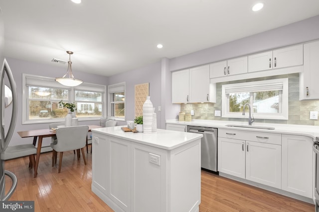 kitchen with stainless steel appliances, a kitchen island, a sink, white cabinetry, and plenty of natural light