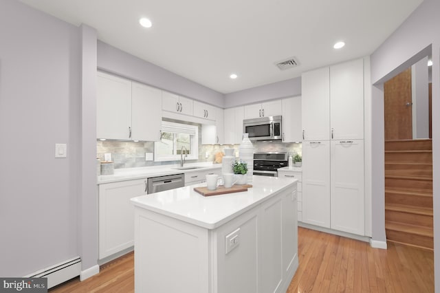 kitchen featuring visible vents, baseboard heating, stainless steel appliances, white cabinetry, and a sink