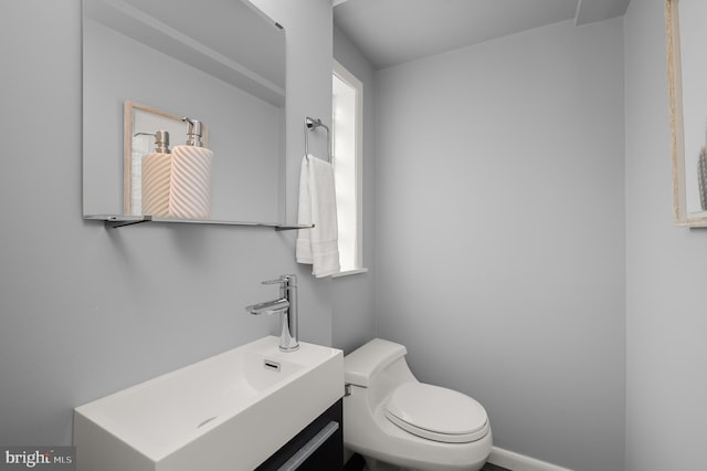 bathroom with baseboards, vanity, and toilet