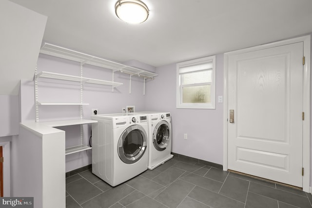 clothes washing area featuring laundry area, washer and clothes dryer, baseboards, and dark tile patterned floors