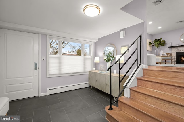 entrance foyer featuring visible vents, stairway, baseboard heating, dark tile patterned floors, and a high end fireplace