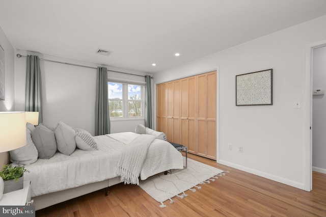 bedroom with recessed lighting, visible vents, baseboards, and wood finished floors