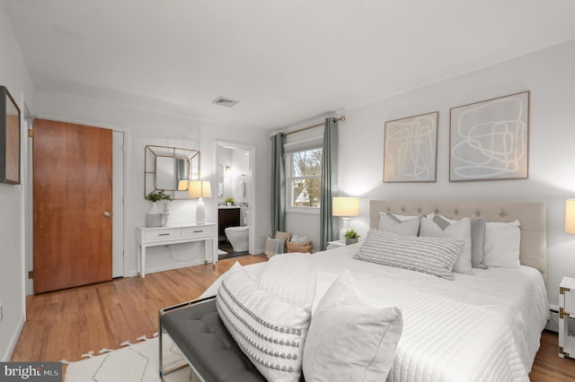 bedroom featuring visible vents, ensuite bath, and wood finished floors