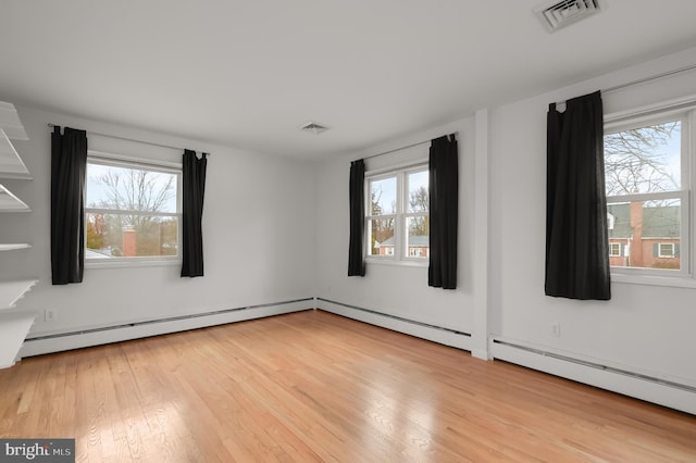 unfurnished room with a baseboard radiator, visible vents, and plenty of natural light