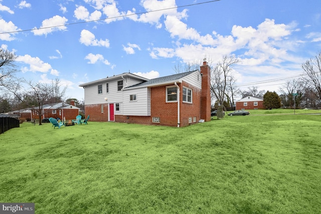 rear view of property featuring crawl space, brick siding, a yard, and a chimney