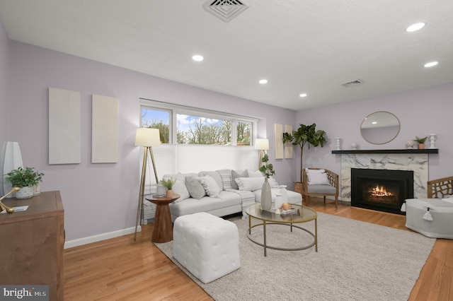 living area with baseboards, a premium fireplace, visible vents, and wood finished floors