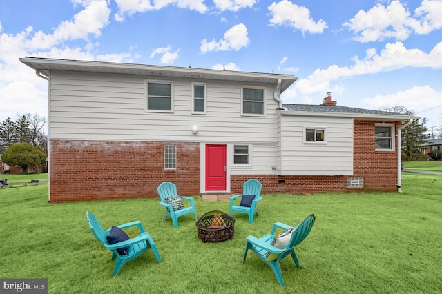 rear view of property featuring a fire pit, brick siding, a lawn, and a chimney