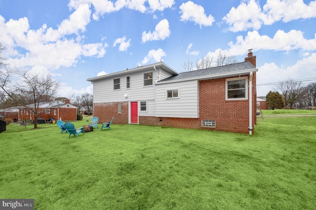 rear view of house featuring brick siding, an outdoor fire pit, a chimney, and a lawn