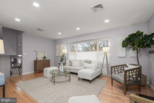 living room with light wood-type flooring, visible vents, and recessed lighting