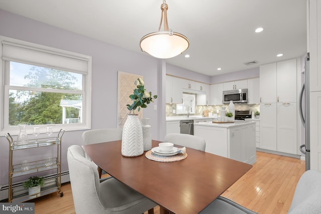 dining area featuring a baseboard heating unit, light wood-type flooring, visible vents, and recessed lighting