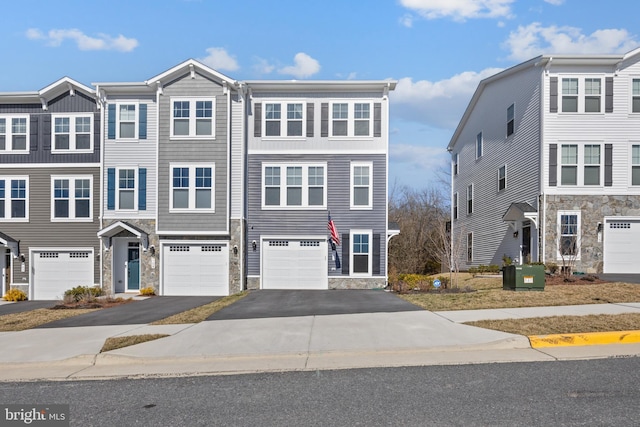 multi unit property with a garage, driveway, and stone siding