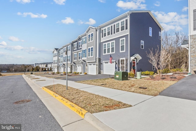 view of front facade with a residential view, central AC, driveway, and an attached garage