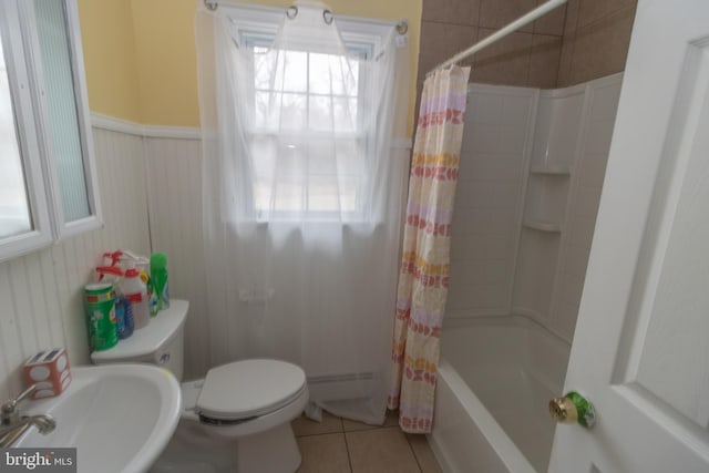 full bathroom featuring toilet, a sink, wainscoting, tile patterned floors, and shower / bath combo