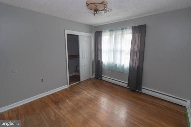 unfurnished room featuring a textured ceiling, baseboard heating, and wood finished floors