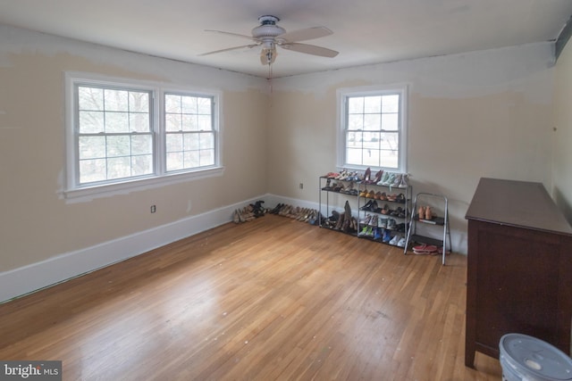 unfurnished room with wood finished floors, a ceiling fan, and baseboards